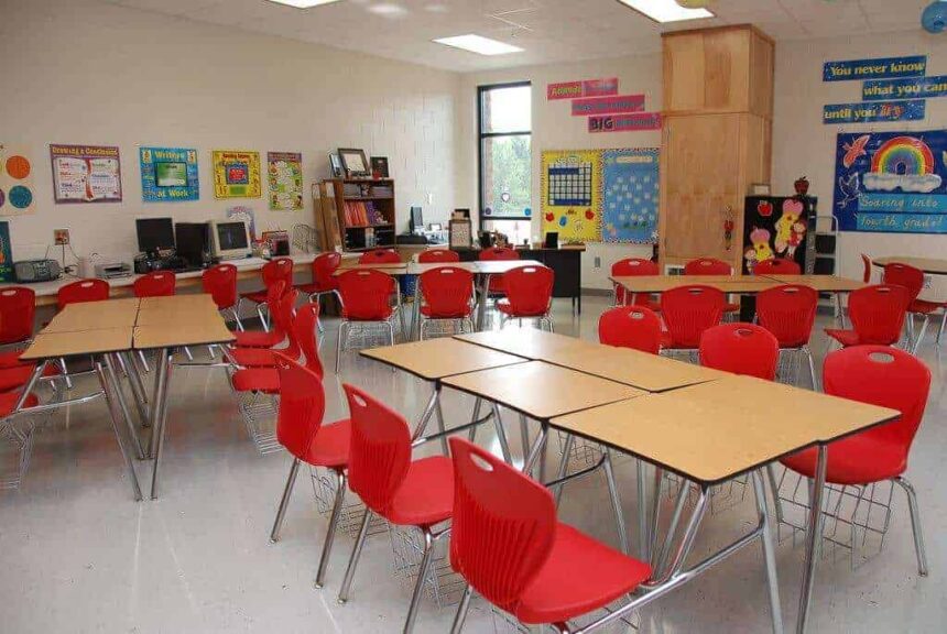 A school classroom with red plastic chairs and long tables