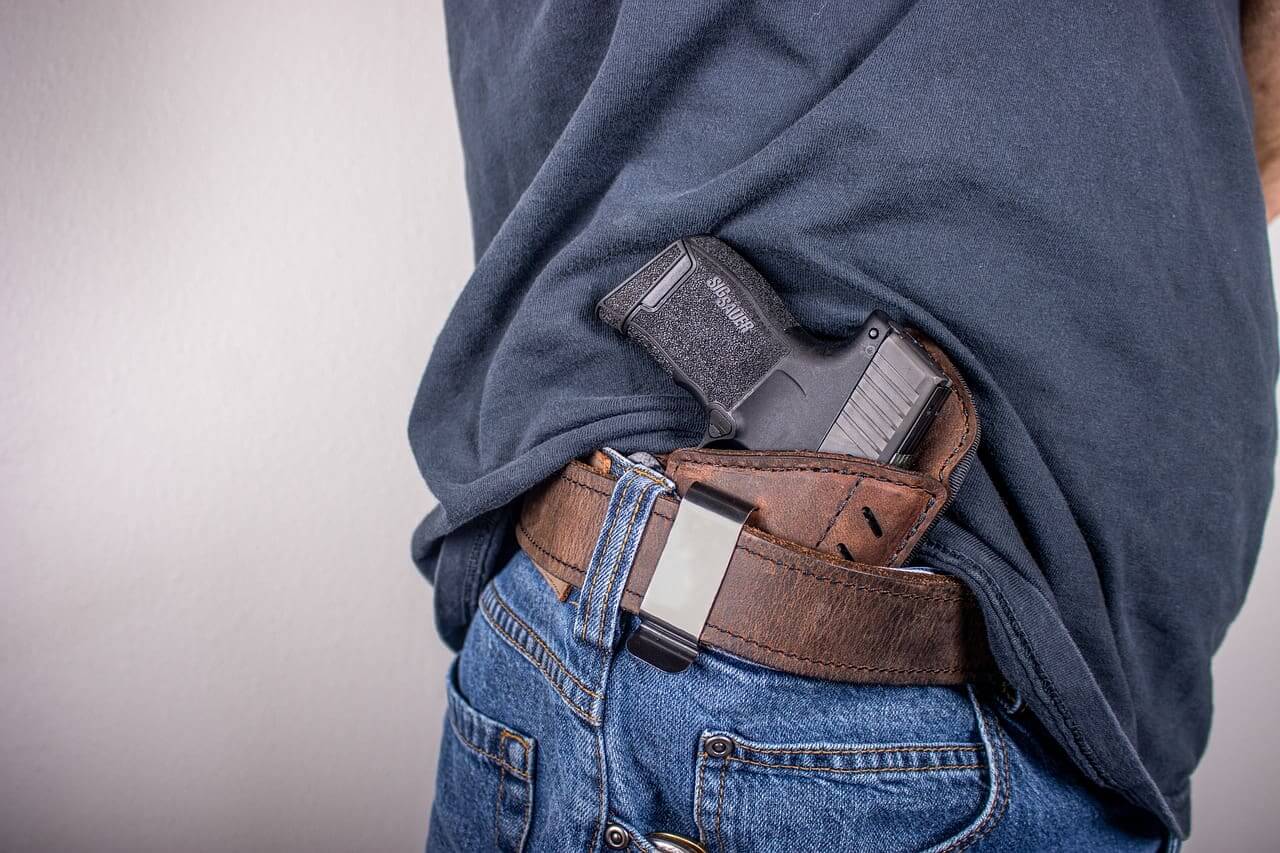Political violence so many citizens have guns making it harder to control gun violence. Man with a gun in his belt.