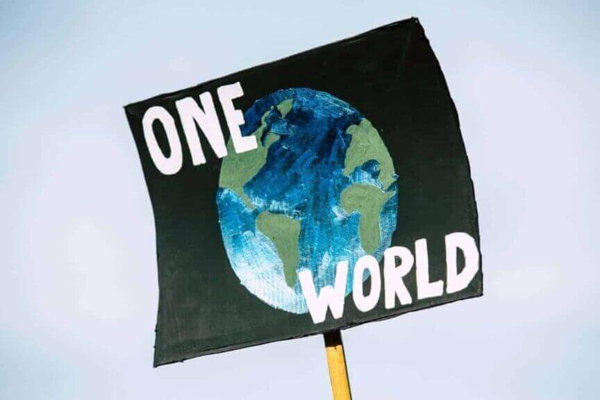 Climate protest sign with the planet painted on a black background and the words ONE WORLD
