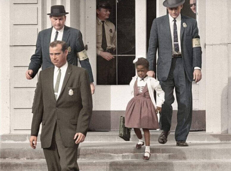 Ruby bridges as a child walking down the steps of a school with three white men around her.