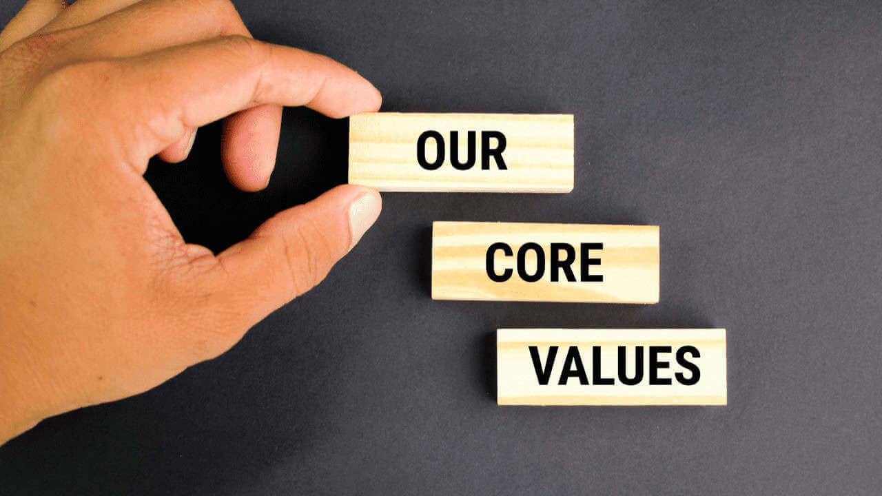 Graphic of a hand setting up word tiles that spell out our core values