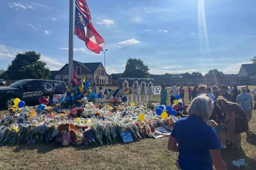 Community members and students gather around a flagpole on the apalachee high school campus near winder, georgia, on sept. 8, leaving flowers and messages to memorialize the four people killed in the sept. 4 shooting there.