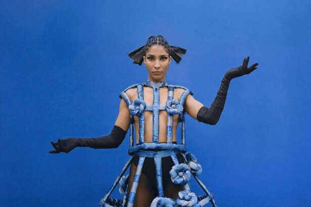 Model on a blue background wearing a futuristic looking light blue dress