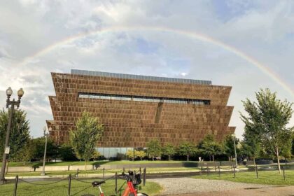Red rideshare bike with a rainbow in the sky in the background