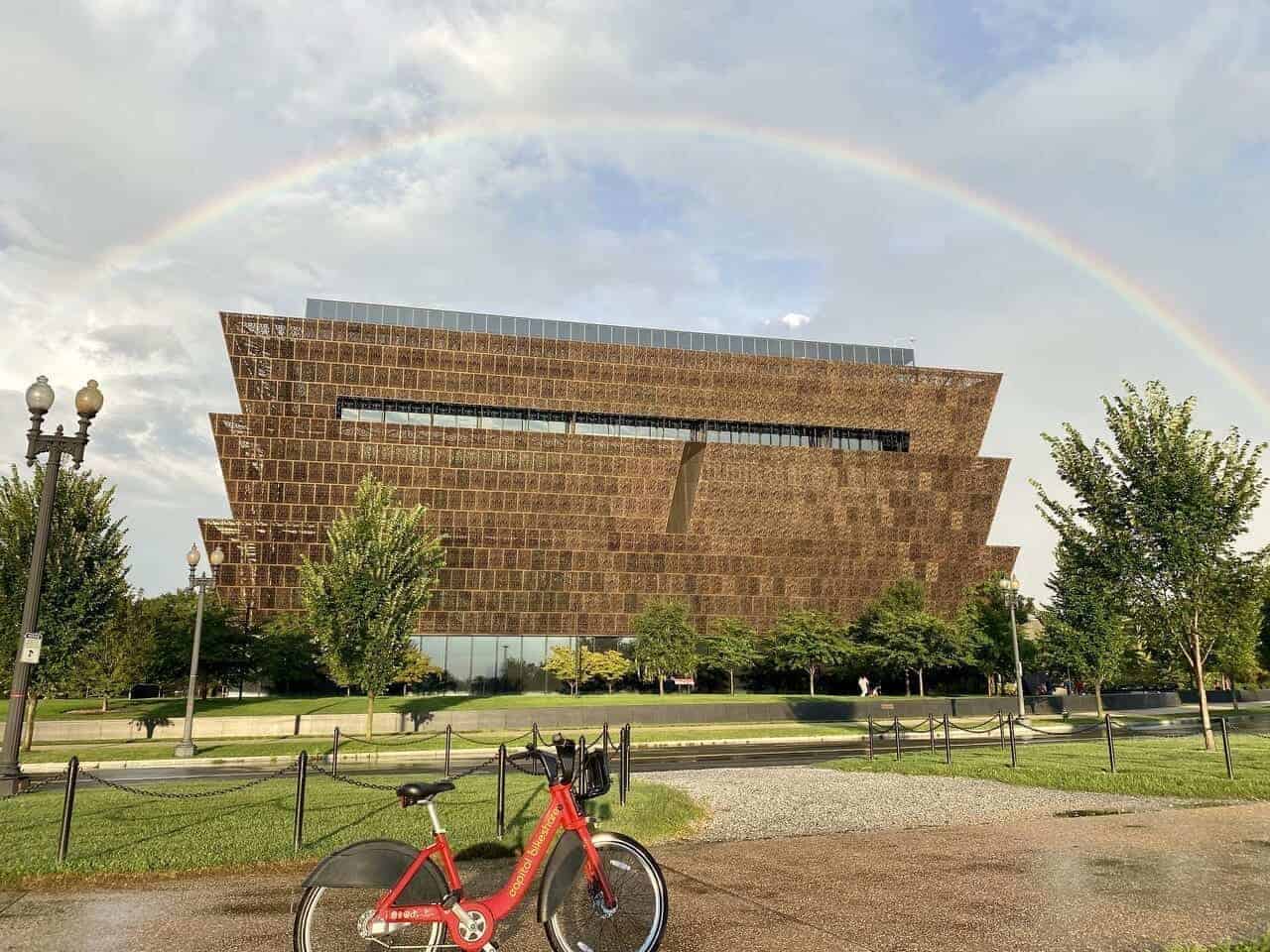 Red rideshare bike with a rainbow in the sky in the background