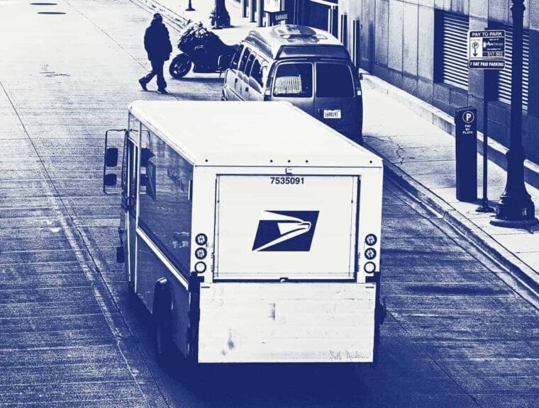A black and white photo of a usps truck driving down a city street. Viewed from above and behind. Mail-in voting order blocked