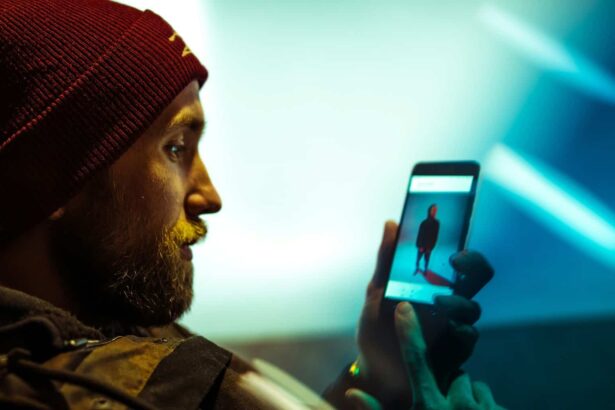 Become less visible online. A man with a beard, wearing a beanie, watching a video on his cell phone.