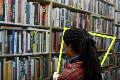 Young girl in a library looking at books on a shelf