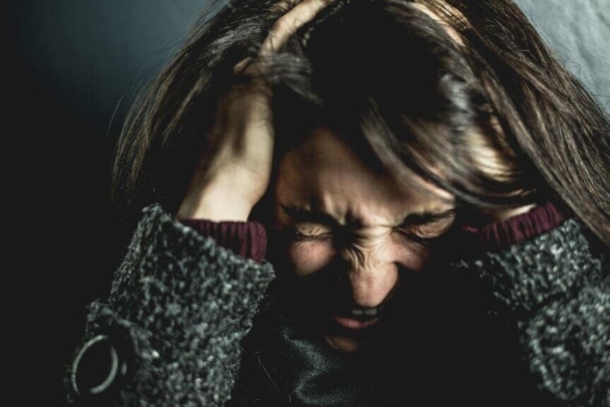 Woman with her head in her hands and a stressed out look on her face