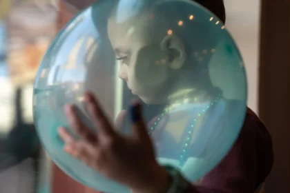 August looks through the glass door of the birthday venue while cradling a balloon on Dec. 9, 2023. He had inoperable brain cancer and depended on Medicaid to pay for full-time home nursing care from a private agency to help his mother take care of him throughout years of health crises
