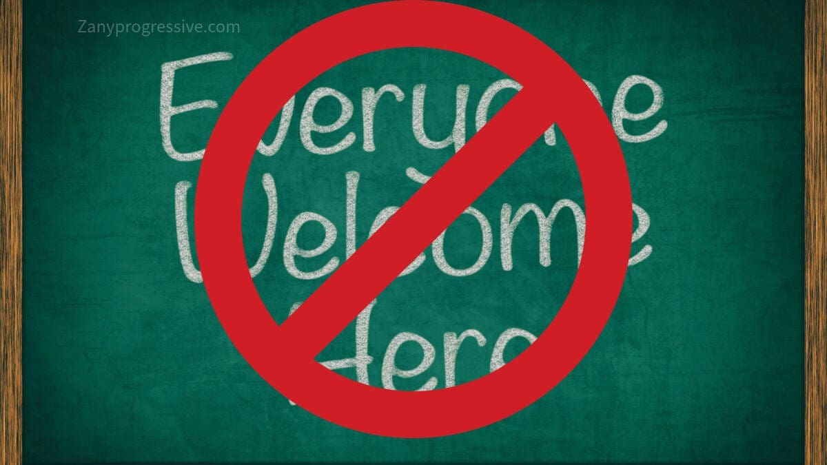 Chalkboard with everyobe welcome here written on it and a red banned symbol over it