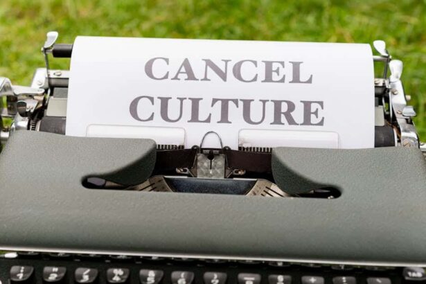 Retro typewriter with 'cancel culture' typed paper on grass background outdoors.