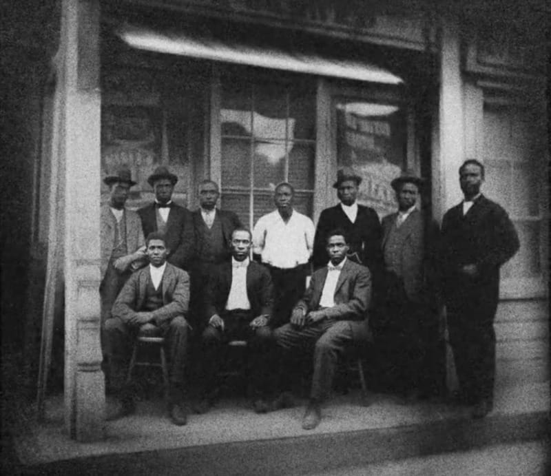eij3 Black and white photo of a group of men in front of a store