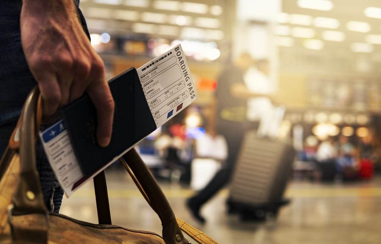 Man holding a passport and boarding pass in an airport