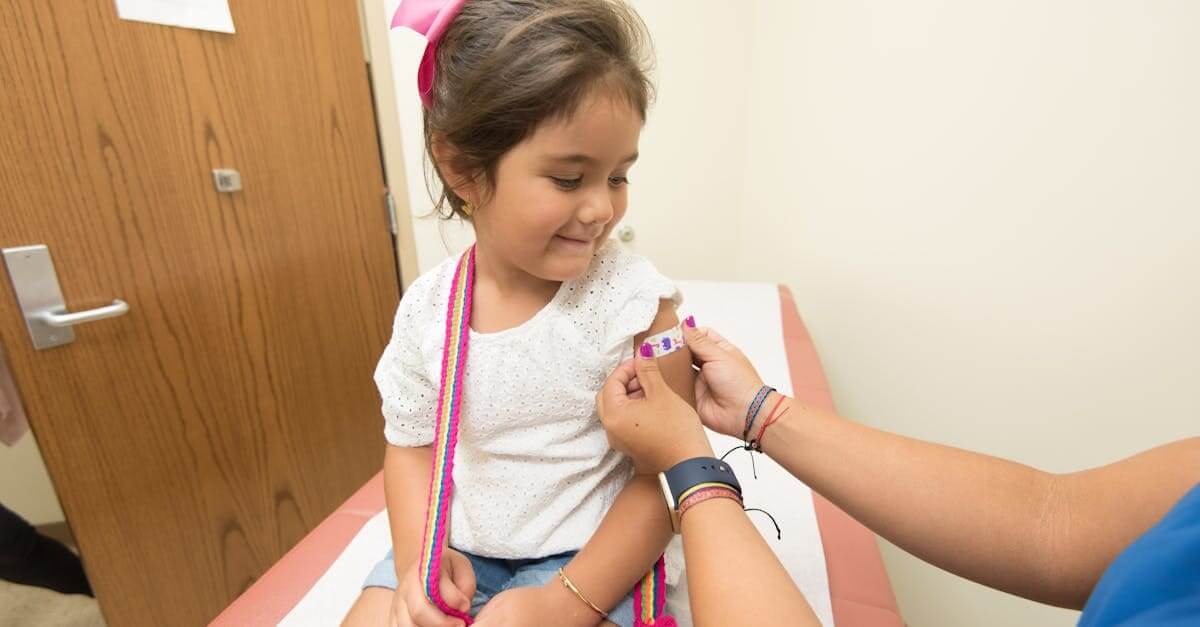 A cheerful young girl receives a band-aid after a vaccination at a clinic.
