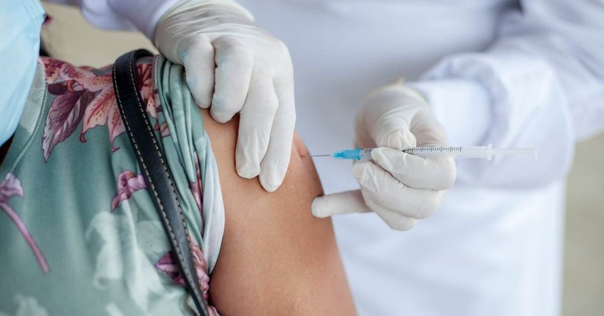Close-up of a healthcare professional giving a vaccine shot to a patient wearing a mask.