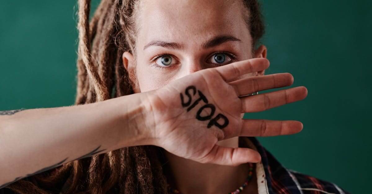 Close-up of a woman holding her hand marked with 'stop' in front of her face, symbolizing protest and strength.