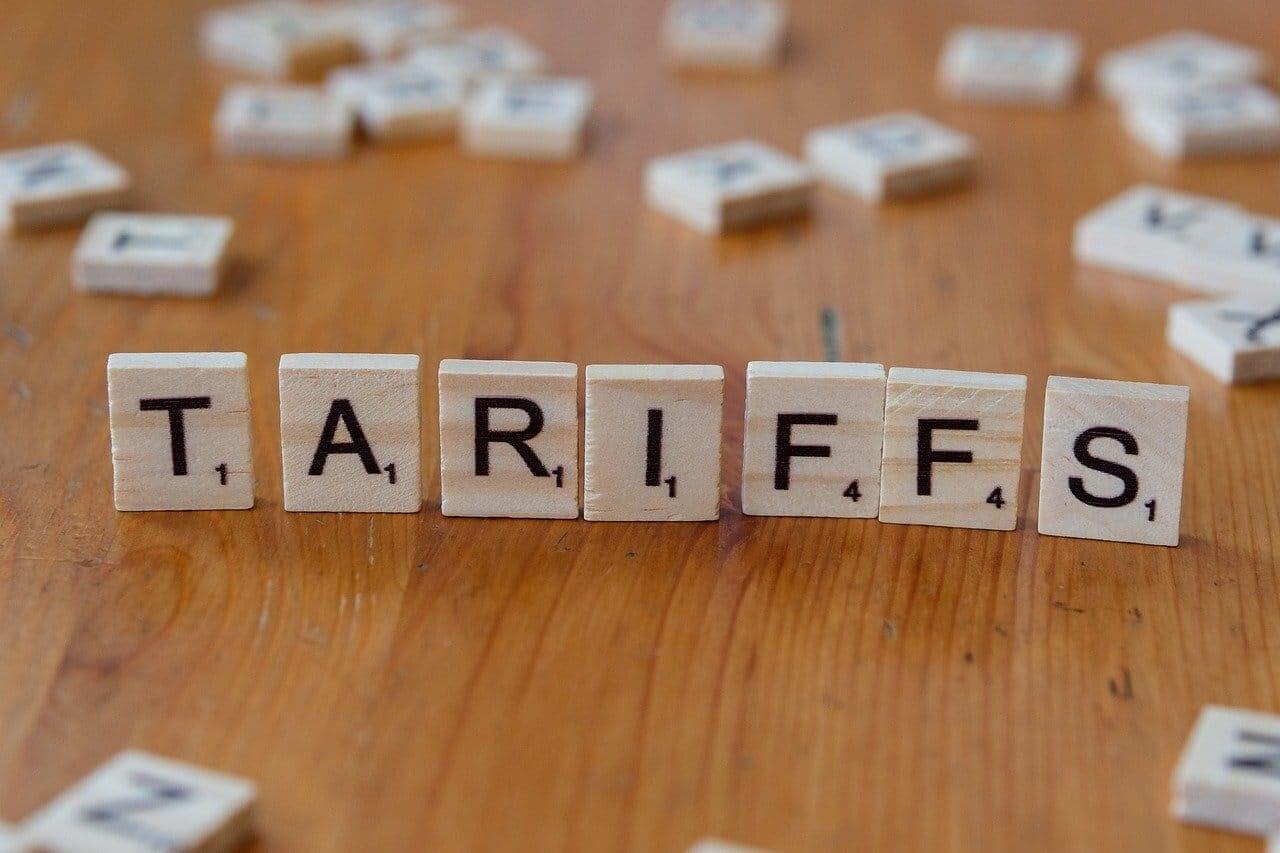 Scrabble tiles standing upright on a wooden table to spell tariffs