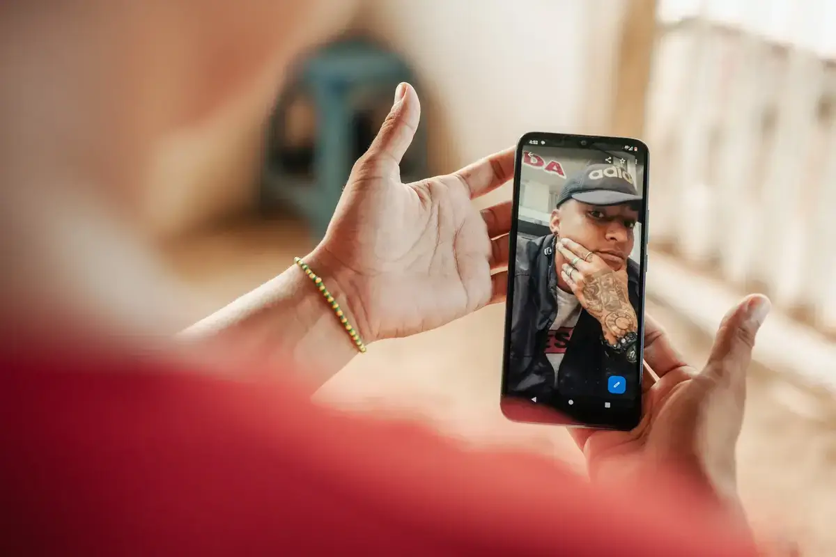 Woman holds a phone displaying a photo of her brother, now in the gulag in el salvador