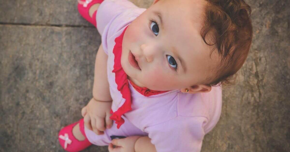 Cute toddler wearing pink, captured from above, gazing up with innocence and curiosity