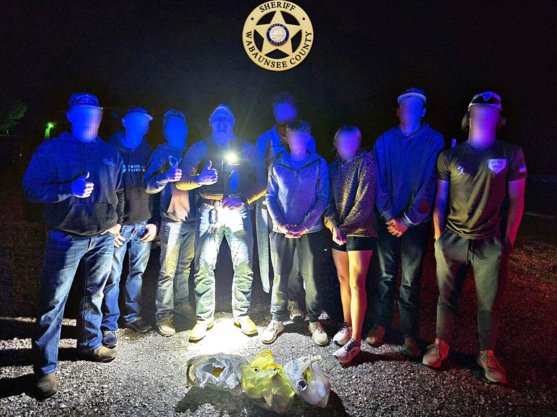 Sheriff posing with teenagers with blurred faces.