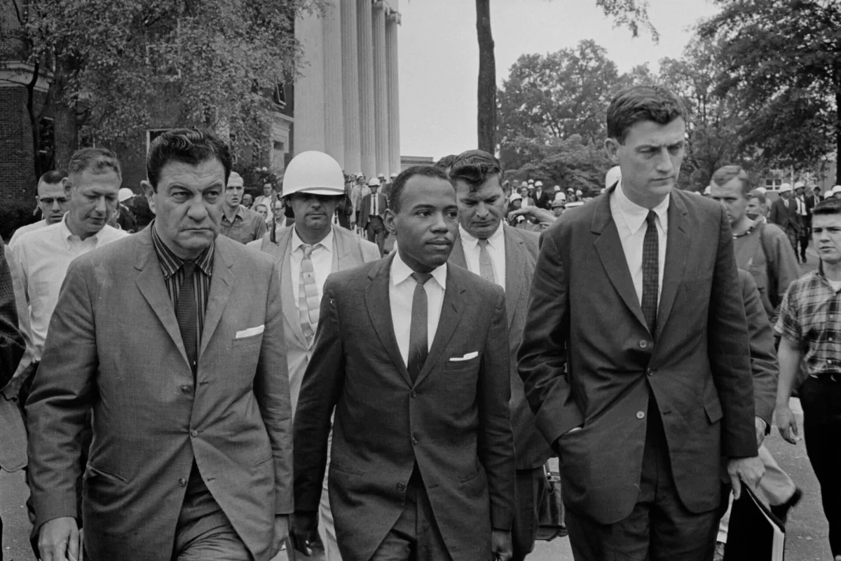 Photograph shows james meredith walking to at ole missaccompanied by u. S. Marshals.