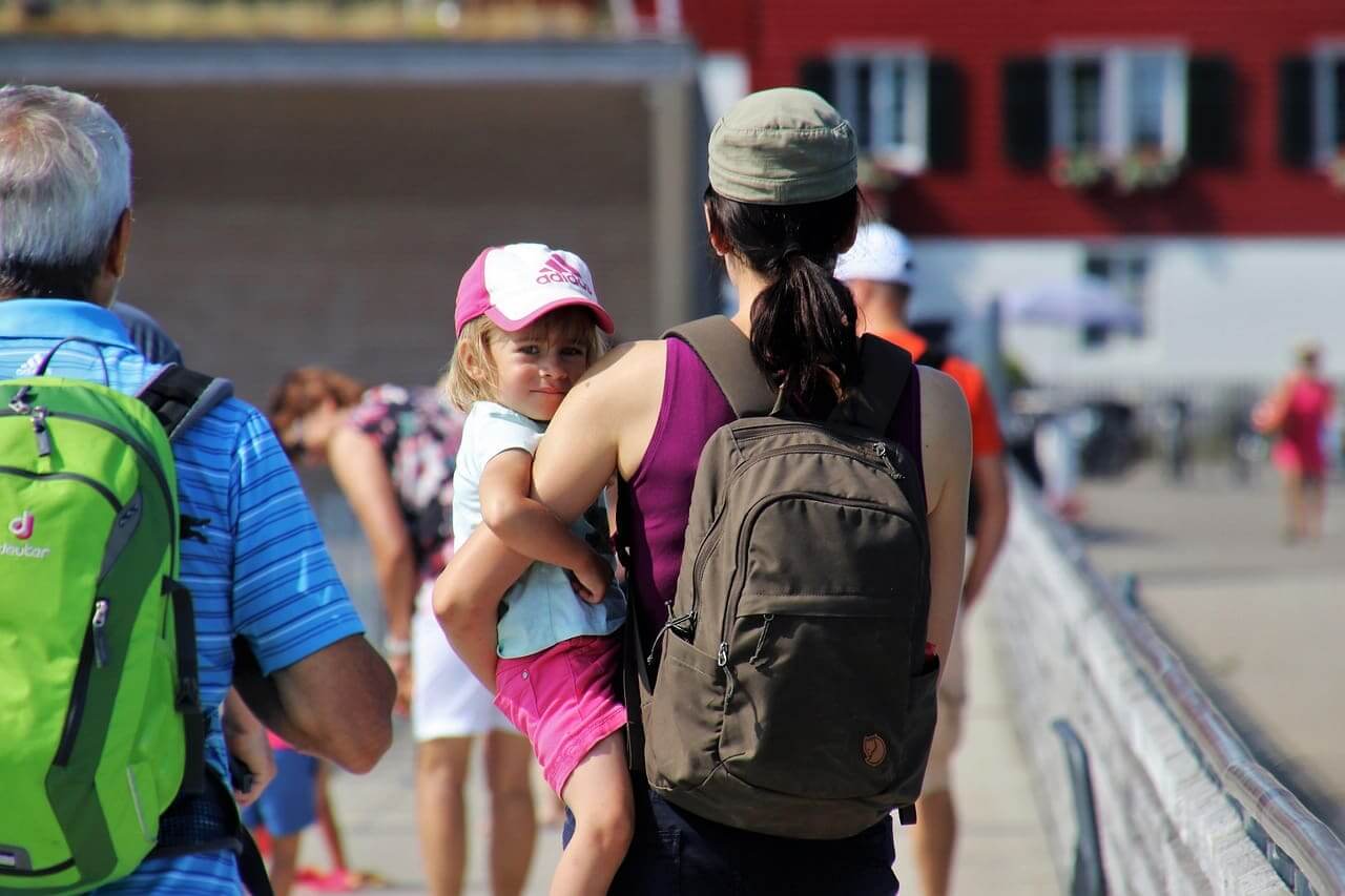 Woman carrying a young child from behind