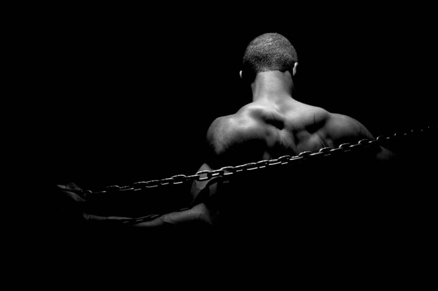 Black man in chains, black background, black and white photo
