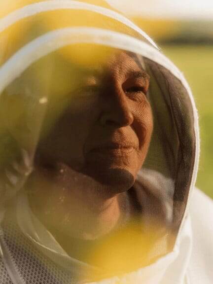 The woman who rescues bees with her face reflected in her coffee.