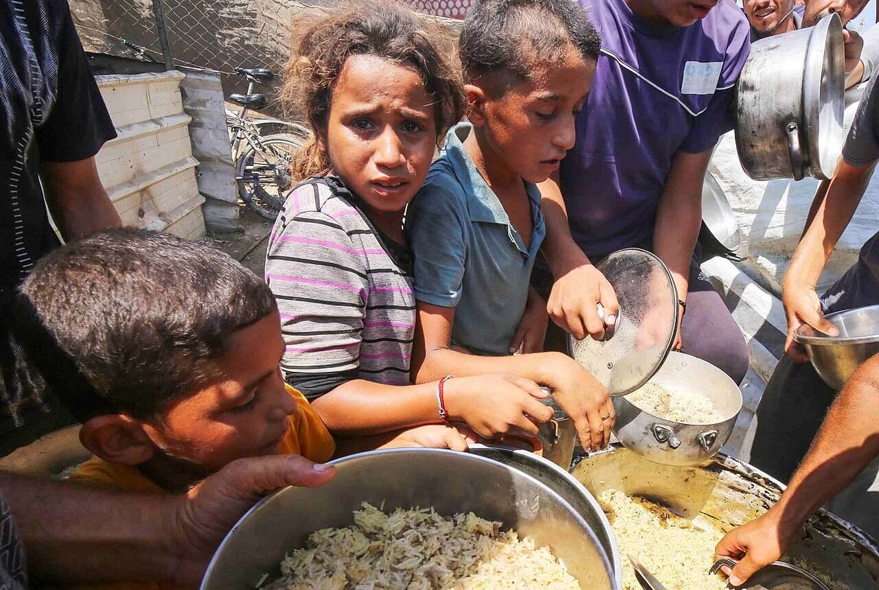 The famine in Gaza began when Israel blocked food from entering the strip. Hungry children line up for food in 2024, before the starvation campaign became a full-blown famine.