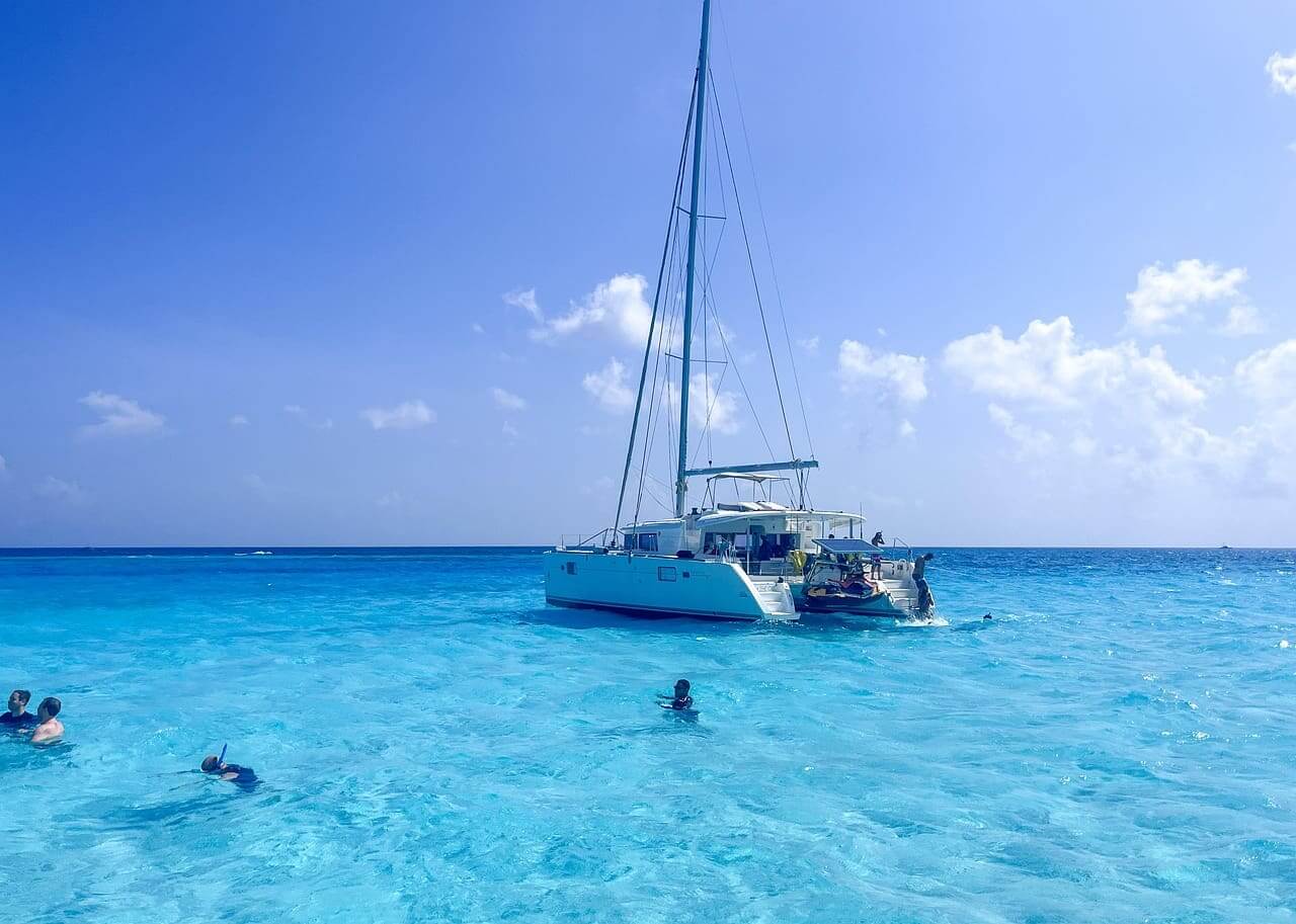 Marine tourism in mexico. Tourists snorkeling in the ocean with a sailboat nearby