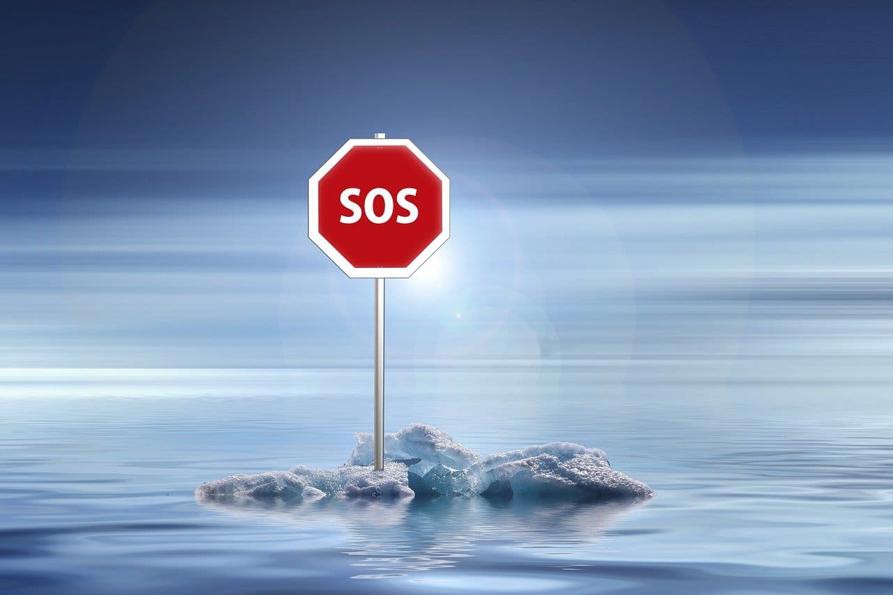 Dangers of climate change is a hoax lie. A melting glacier floating in the ocean with a stop sign on it that says sos.