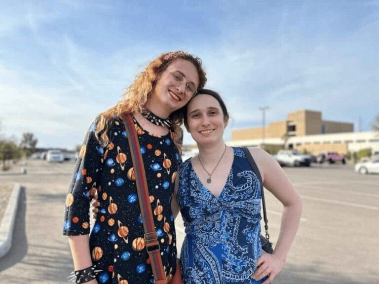 Two women standing next to each other with arms around shoulders