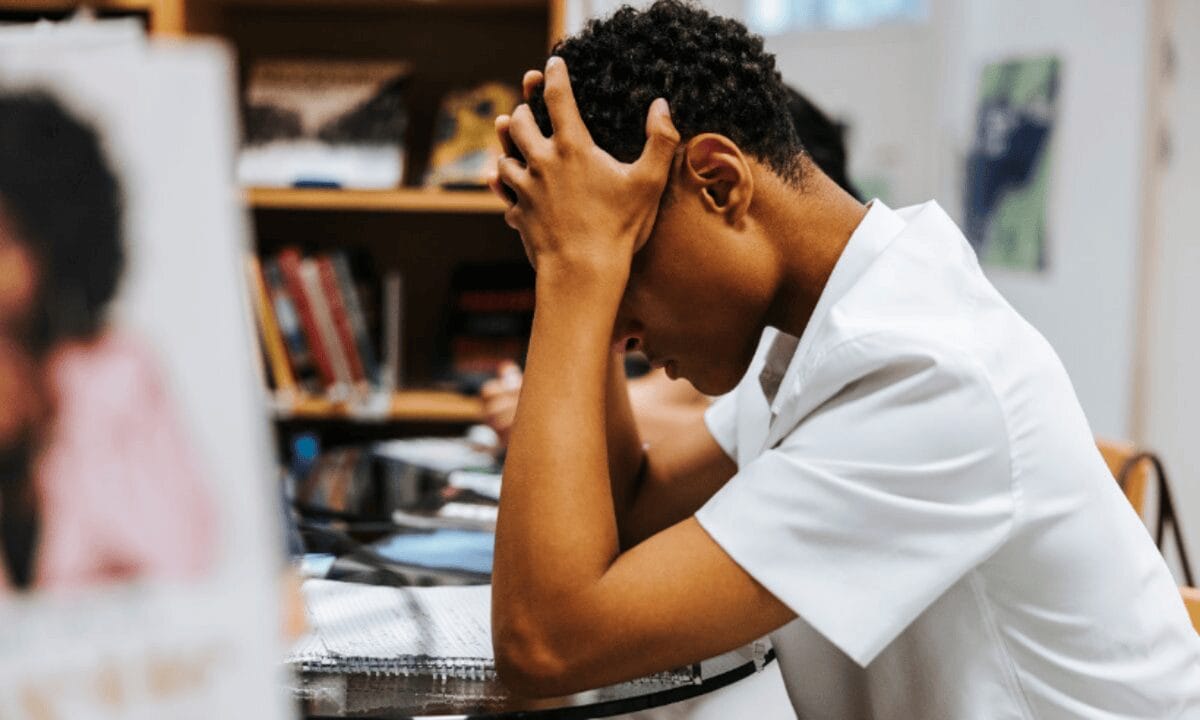 Young student at his desk with his head in his hands