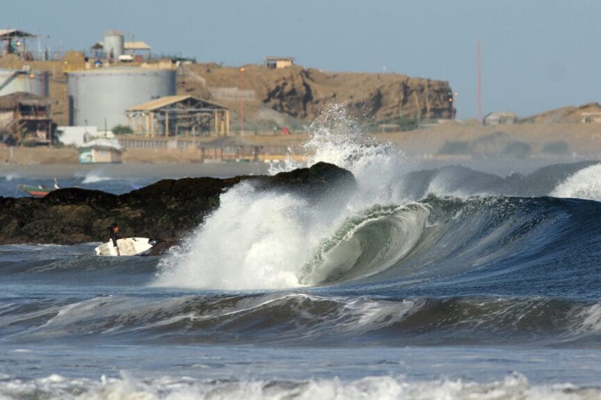 Surfer entering the sea with crashing waves