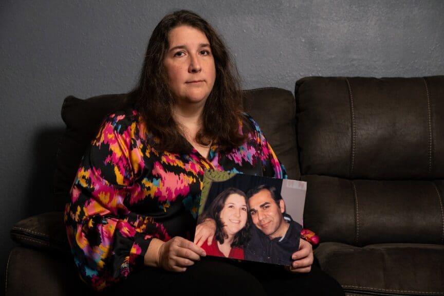 Woman holding photo of her with her husband who was arrested by ice