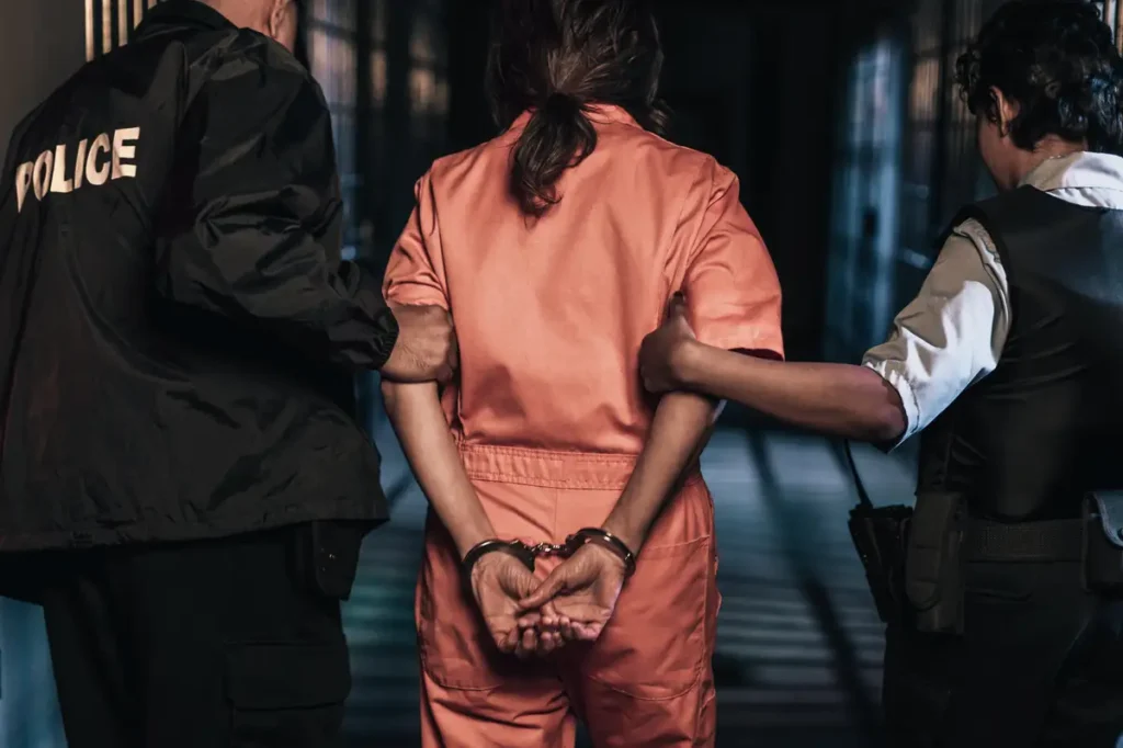 Mass incarceration police lead a female prisoner down a hallway