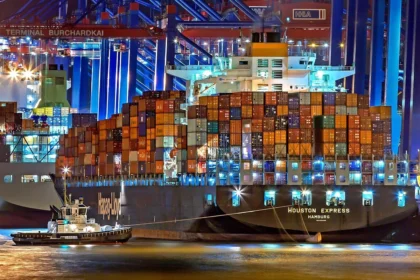Port at night with bright lights and a barge loaded with shipping containers. Tariff refunds