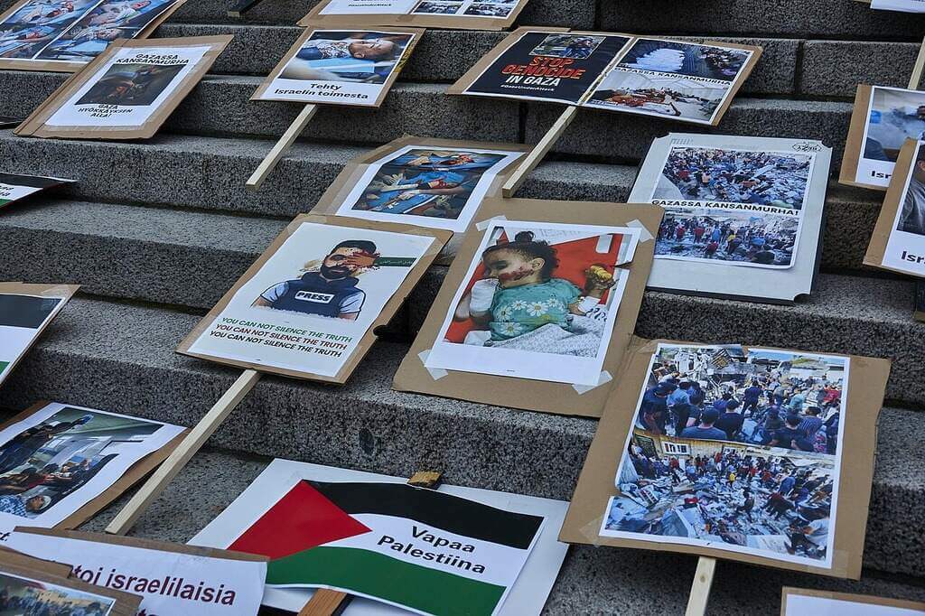 Signs from a stop the genocide protest with images of children injured or killed in gaza.