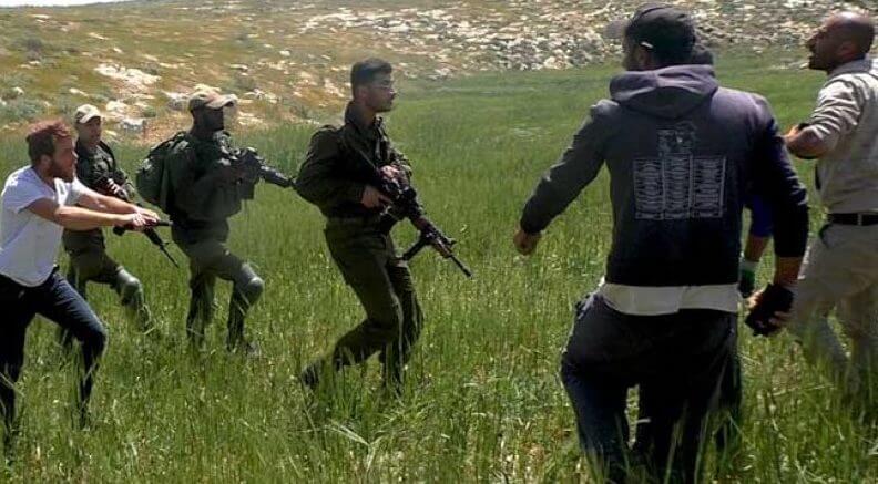 Photo of israeli settler violence as settlers confront farmers in the west bank with guns.
