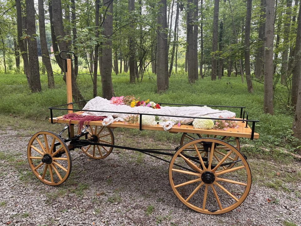 A green burial funeral service. The body is wrapped in a shroud and transported on a wooden wagon